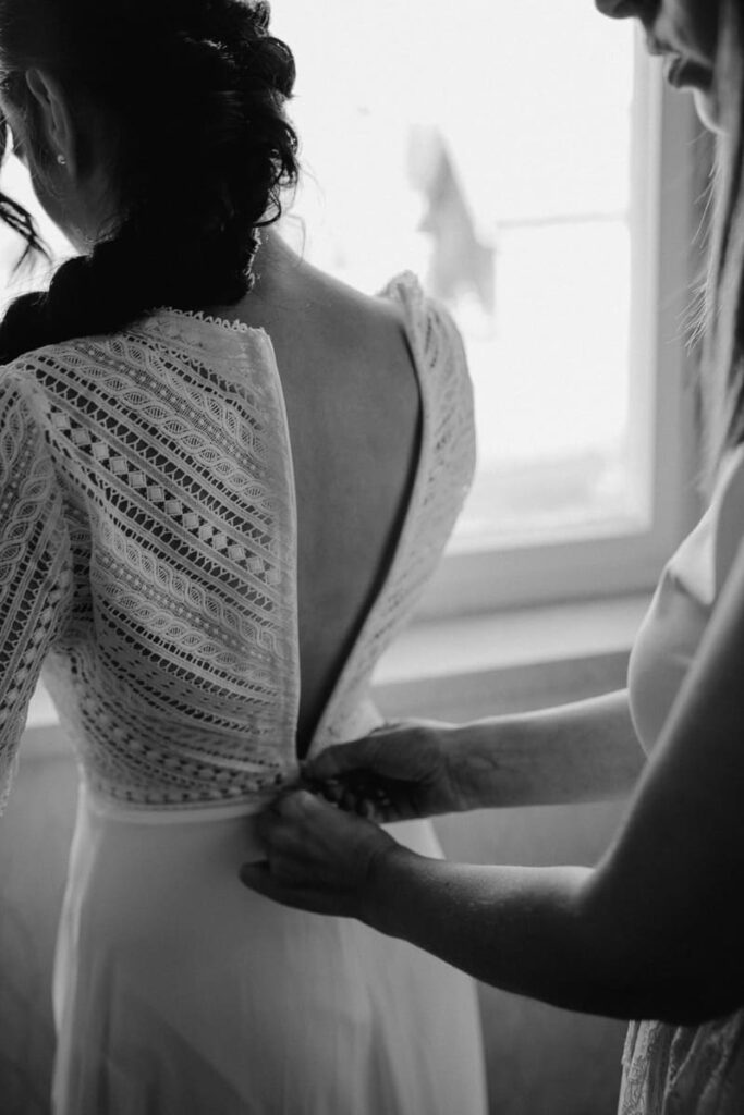 Braut beim Anziehen ihres Hochzeitskleides