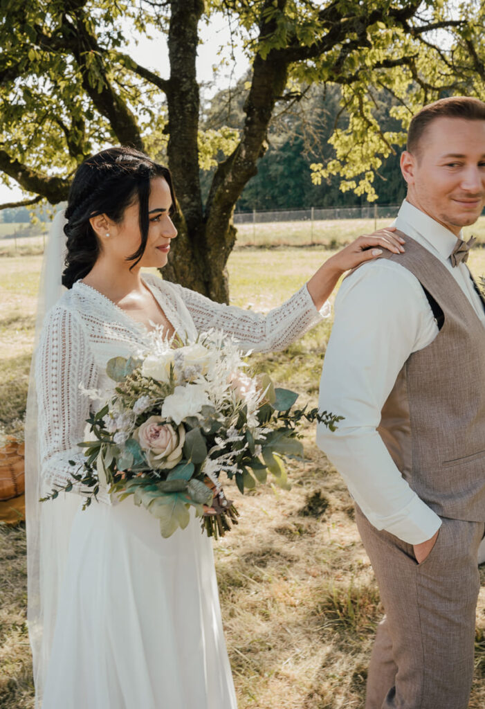 Braut legt Hand auf Bräutigam bei einem Boho Styled Shooting auf einer Wiese im Altmühltal