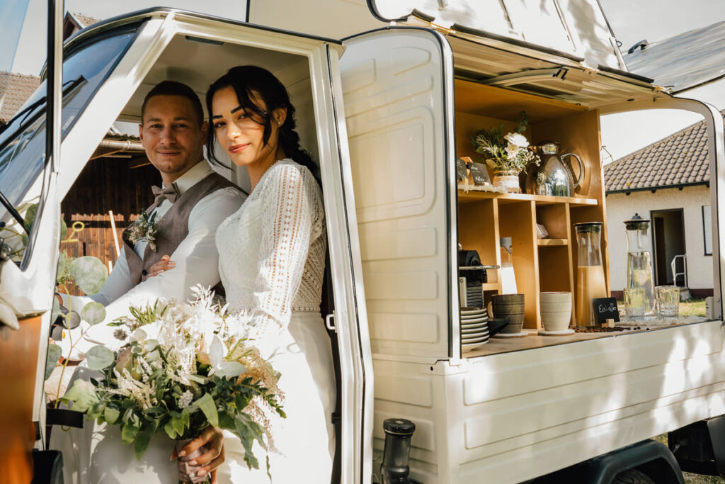 Brautpaar sitzend in einer Ape bei einem Boho Styled Shooting auf einer Wiese im Altmühltal
